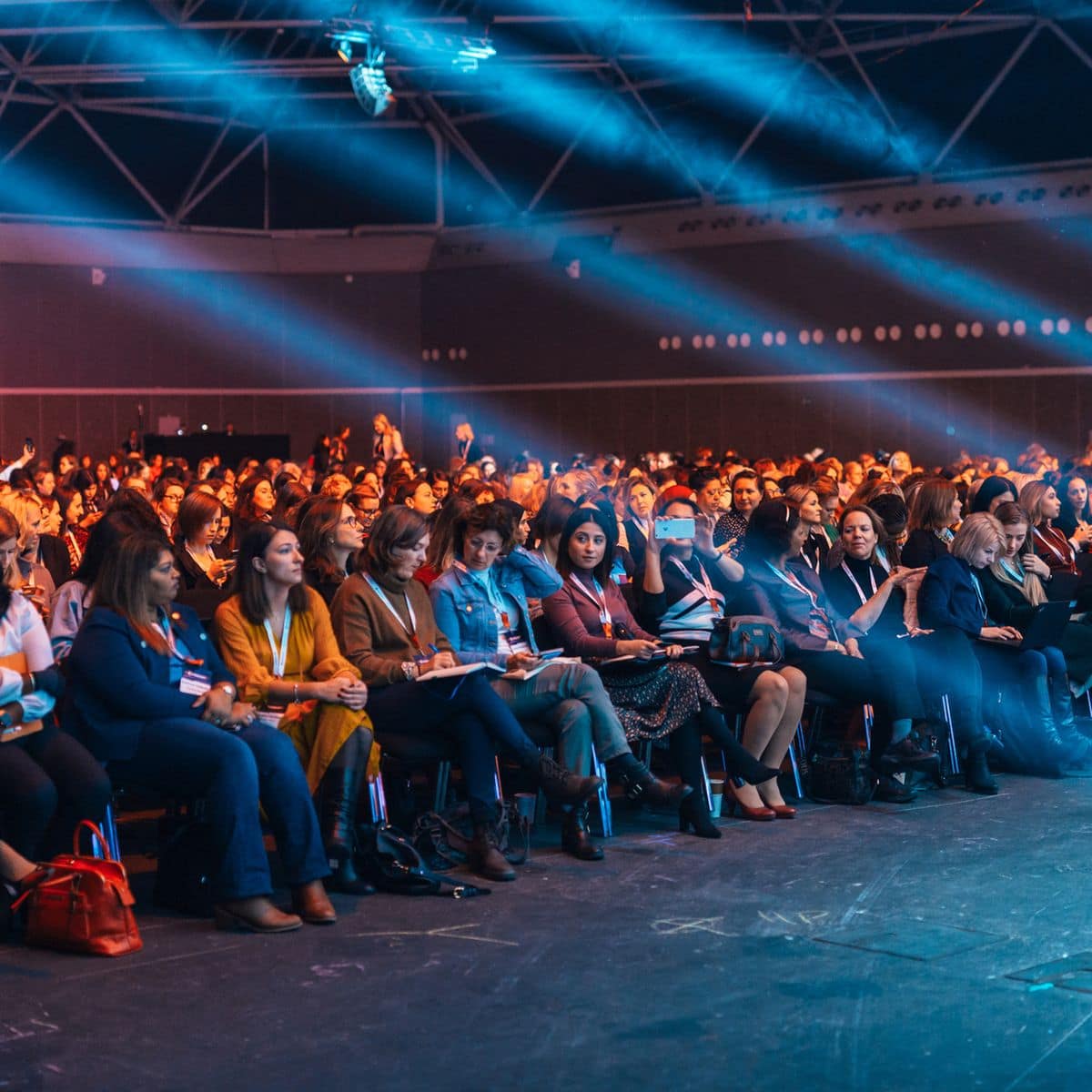 Audience seated in a large auditorium under stage lighting