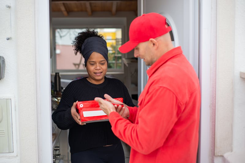 Courier handing package to smiling customer at door