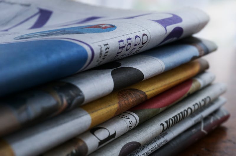Stack of colorful newspapers on wooden table