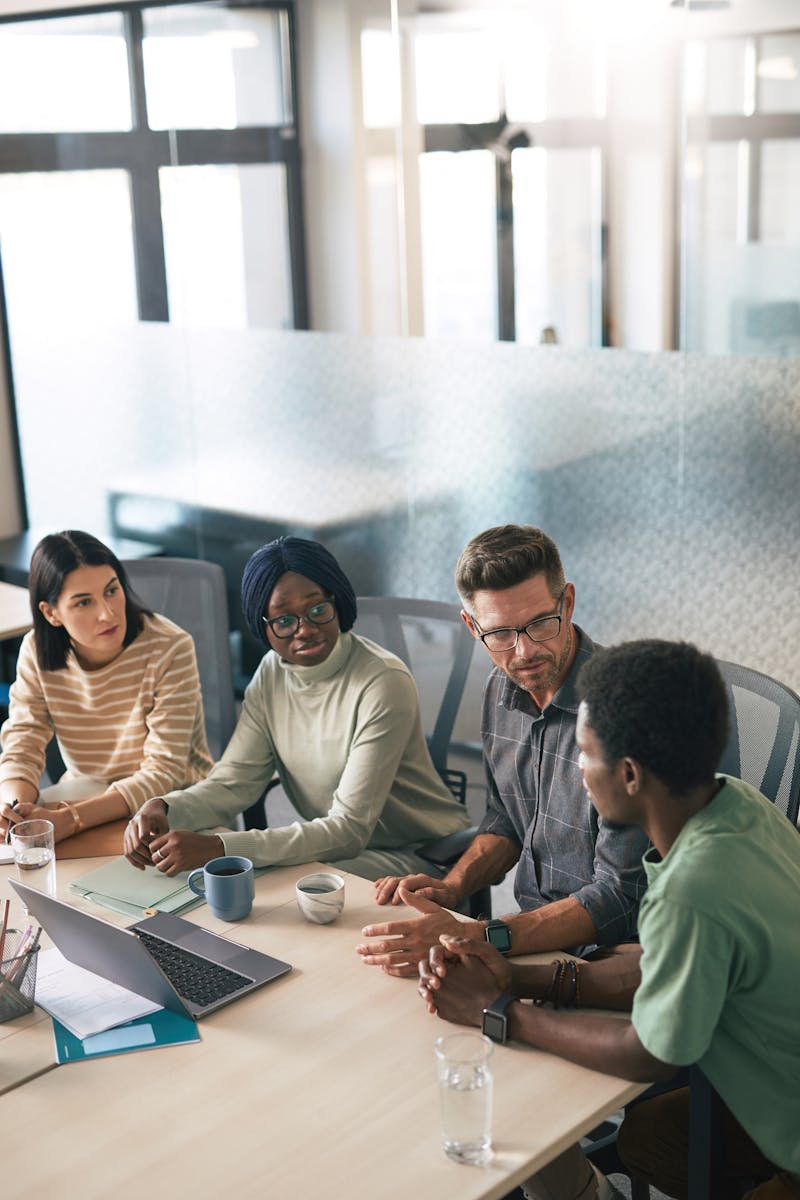 Diverse team discussing in modern office with laptops
