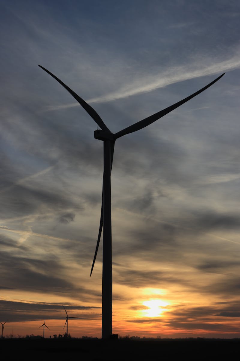 Wind turbine silhouette against vibrant sunset